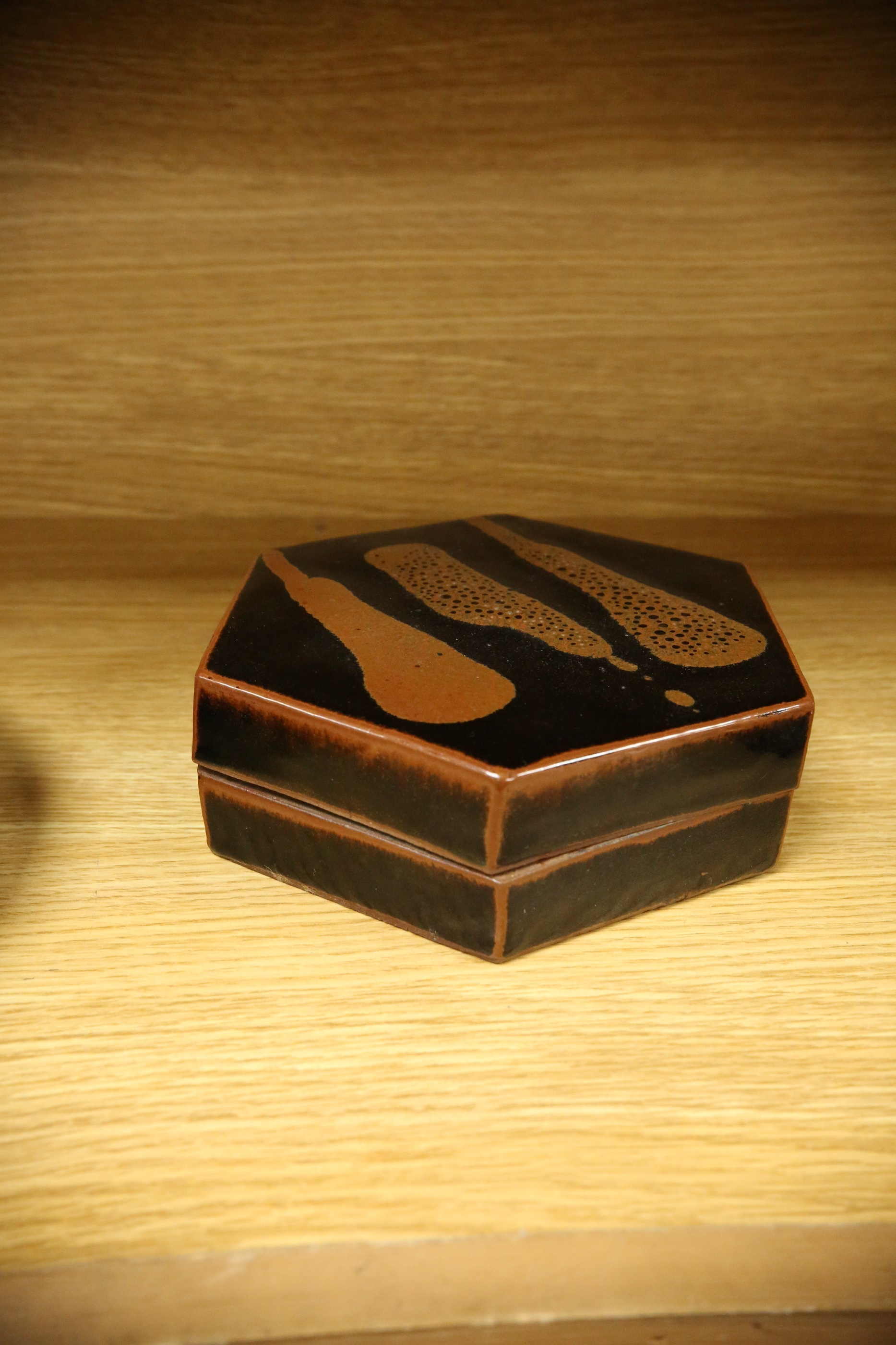 A Japanese studio tenmoku glazed hexagonal box and cover, unmarked, 18cm wide. Condition - good